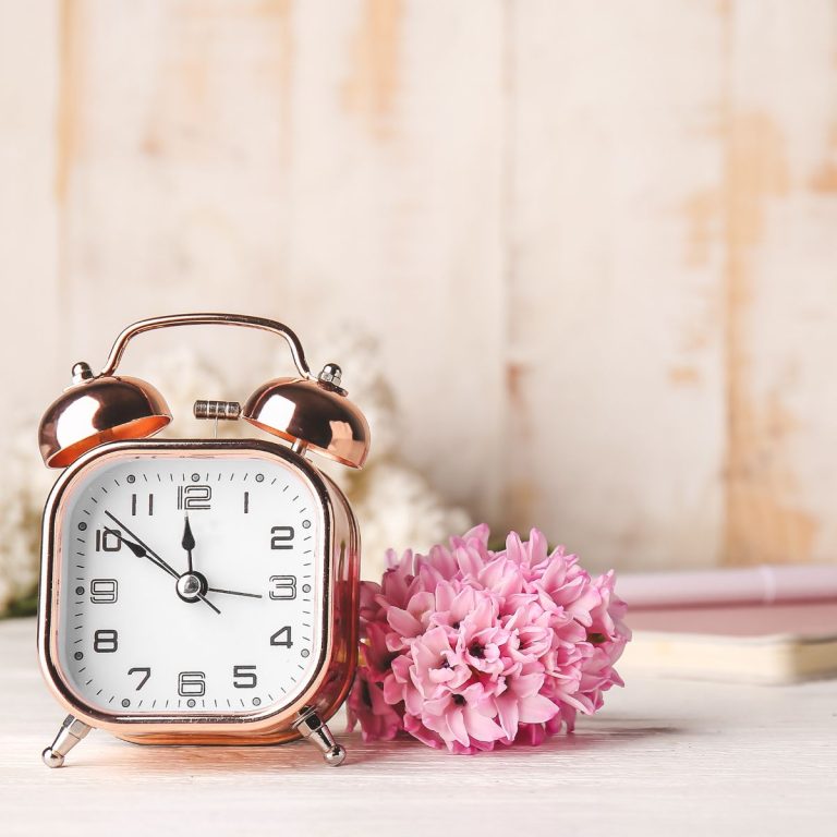 Alarm clock and flowers on a table.