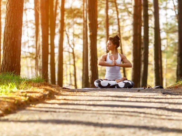 Woman in yoga pose, surraounded by beautiful autumn scenery