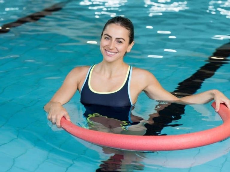 Young girl in the pool exercising with a pool noodle