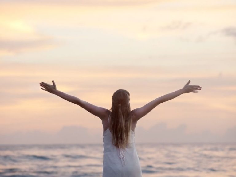 Girl greeting the day by the ocean