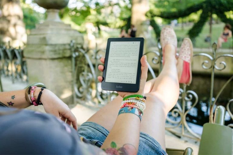 woman sitting outside reading on her digital reader