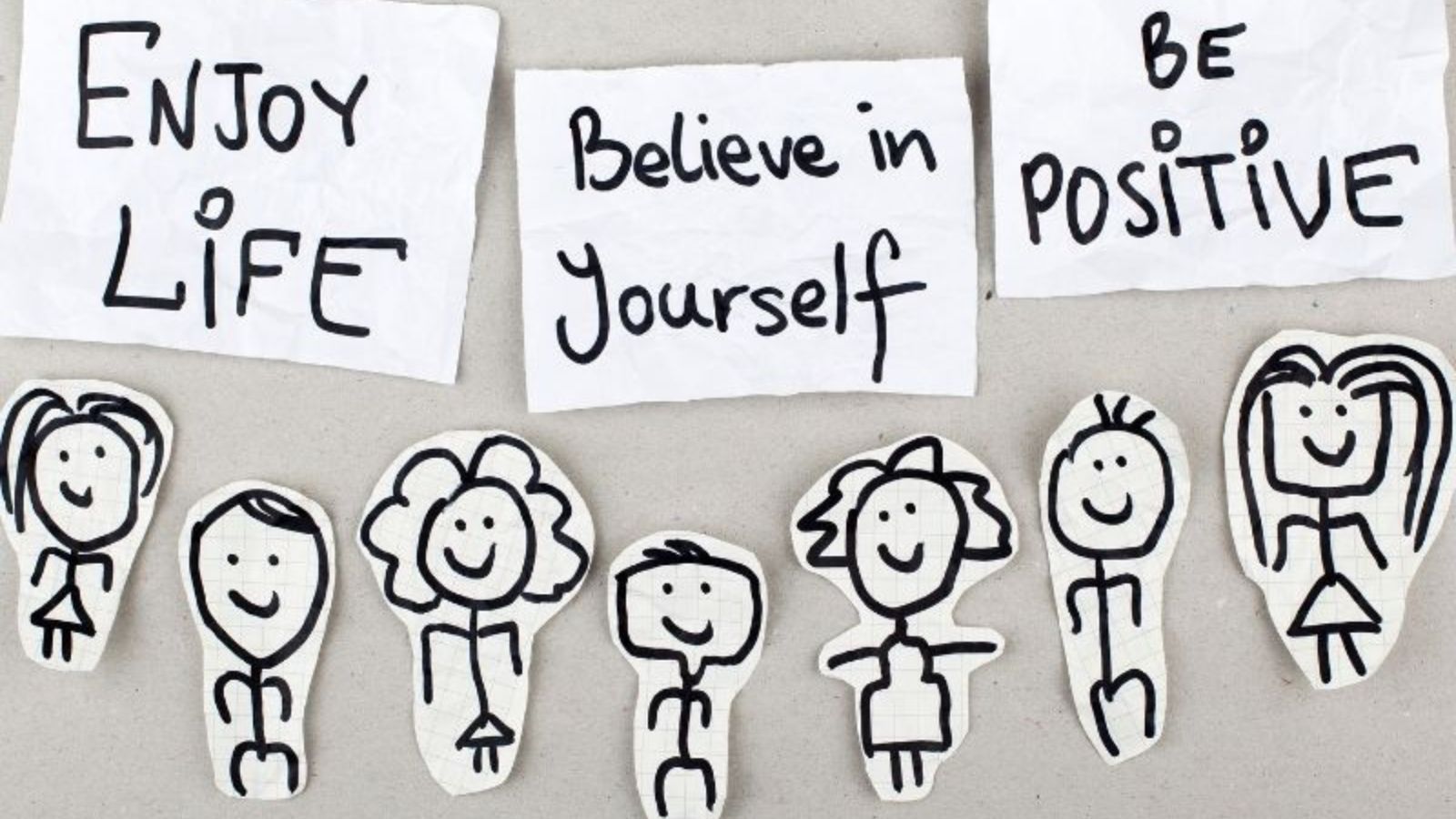 Enjoy life, believe in yourself, be positive - notes on white paper with stick figures underneath.
